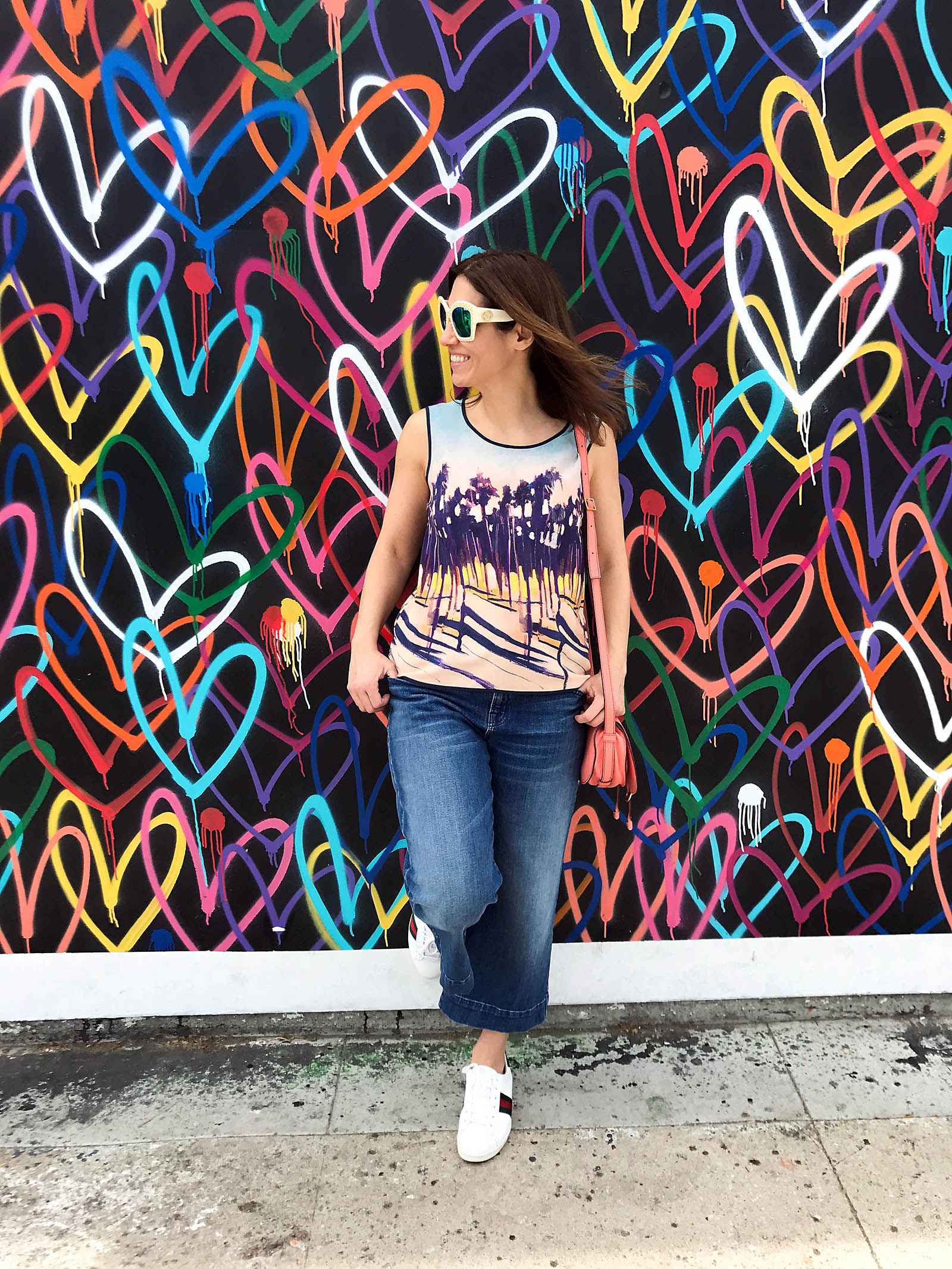 Anna Roufos Sosa in front of a heart print wall in LA wearing Mother of Pearl and Gucci.